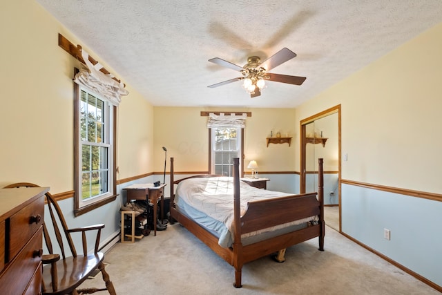 bedroom featuring ceiling fan, a baseboard radiator, a textured ceiling, light carpet, and a closet