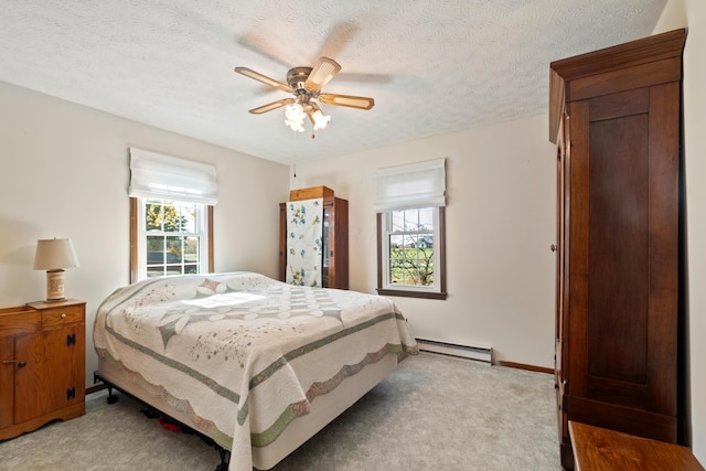 carpeted bedroom featuring ceiling fan, a textured ceiling, and a baseboard heating unit