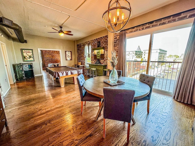 dining space with brick wall, ceiling fan with notable chandelier, hardwood / wood-style flooring, and pool table