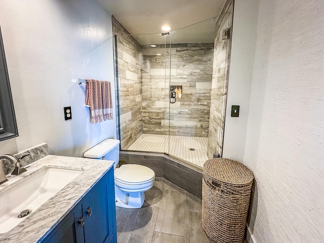 bathroom with a shower with door, vanity, and toilet