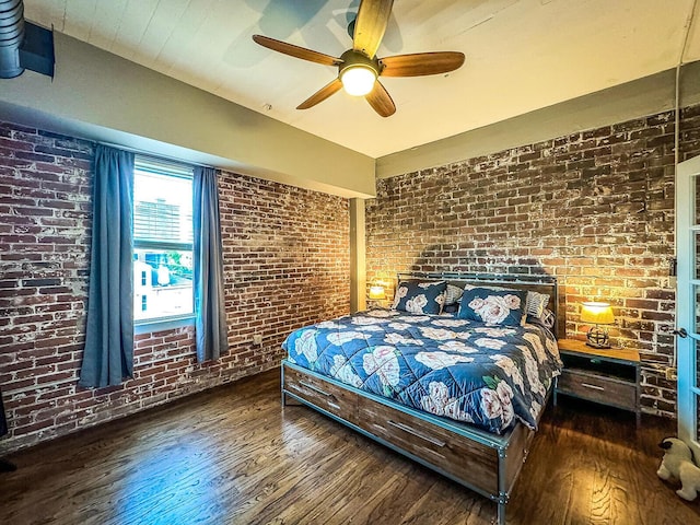 bedroom with dark hardwood / wood-style floors, ceiling fan, and brick wall