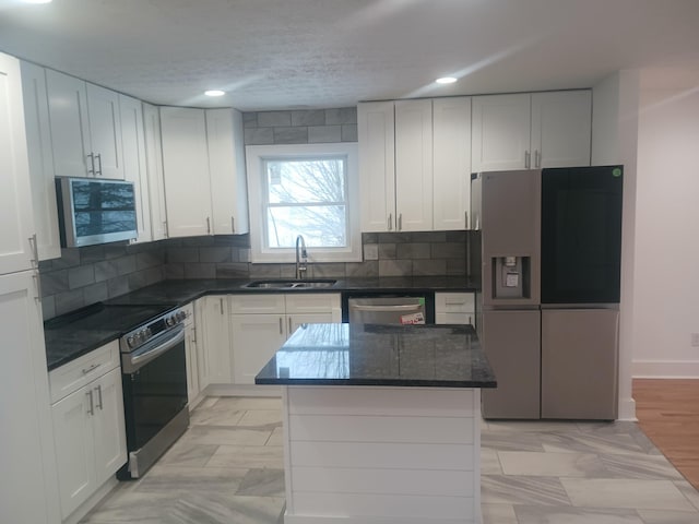 kitchen featuring white cabinets, appliances with stainless steel finishes, sink, and a center island