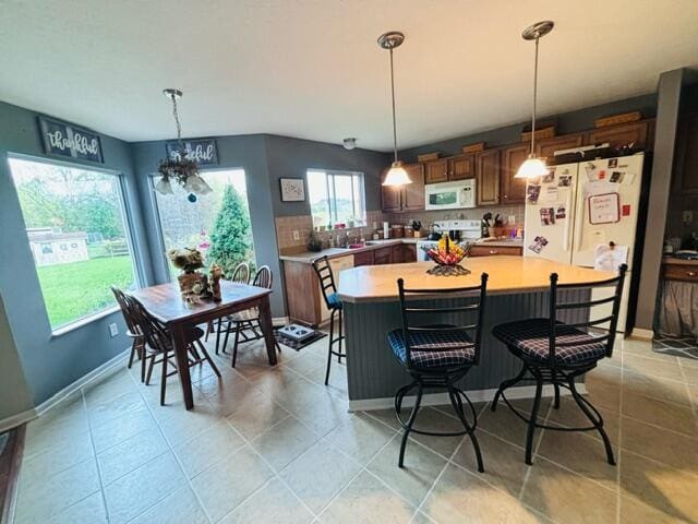 kitchen featuring pendant lighting, a notable chandelier, a center island, and white appliances