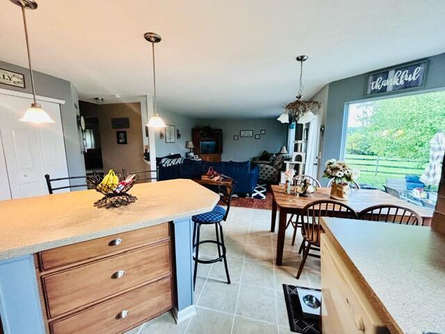 kitchen with a kitchen breakfast bar, light brown cabinets, light tile patterned floors, and pendant lighting