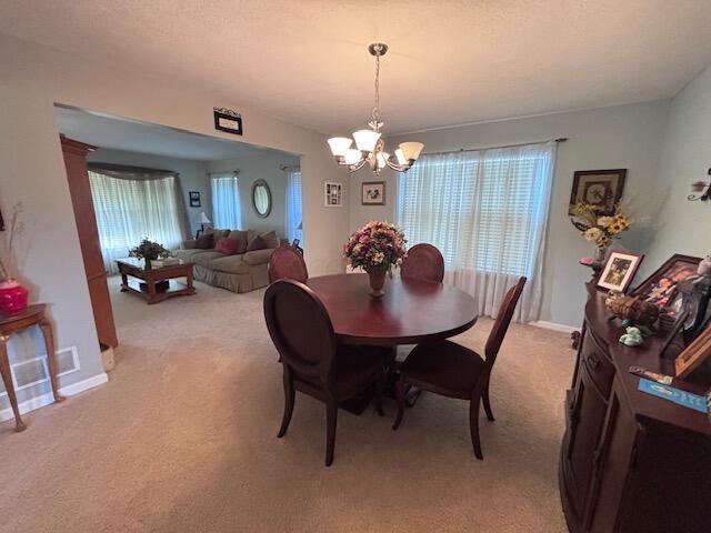 carpeted dining room featuring a notable chandelier