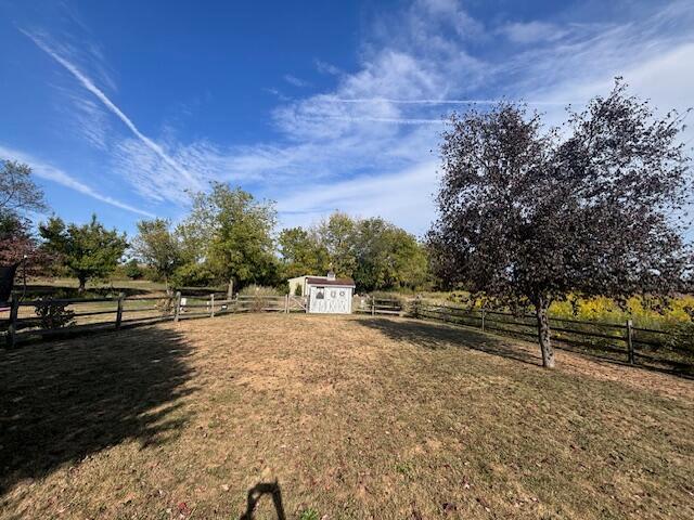 view of yard with a rural view and a shed