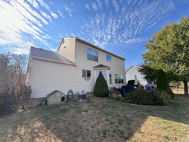 rear view of property featuring a lawn and central AC