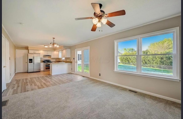 unfurnished living room featuring light carpet, ceiling fan with notable chandelier, and ornamental molding