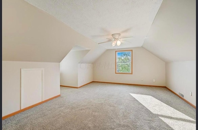 additional living space featuring a textured ceiling, ceiling fan, lofted ceiling, and light carpet