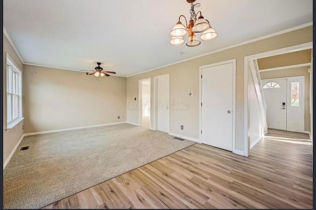 interior space with hardwood / wood-style floors, ceiling fan with notable chandelier, and ornamental molding