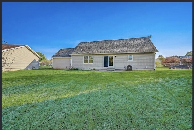 rear view of house featuring a lawn and central air condition unit