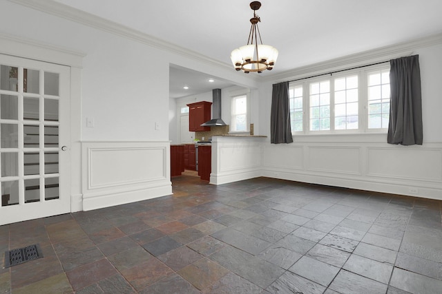 unfurnished dining area featuring plenty of natural light, crown molding, and a notable chandelier