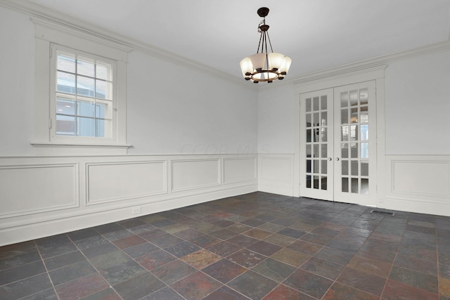 spare room with an inviting chandelier, crown molding, and french doors