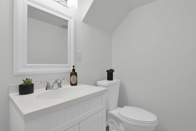 bathroom featuring vanity, lofted ceiling, and toilet