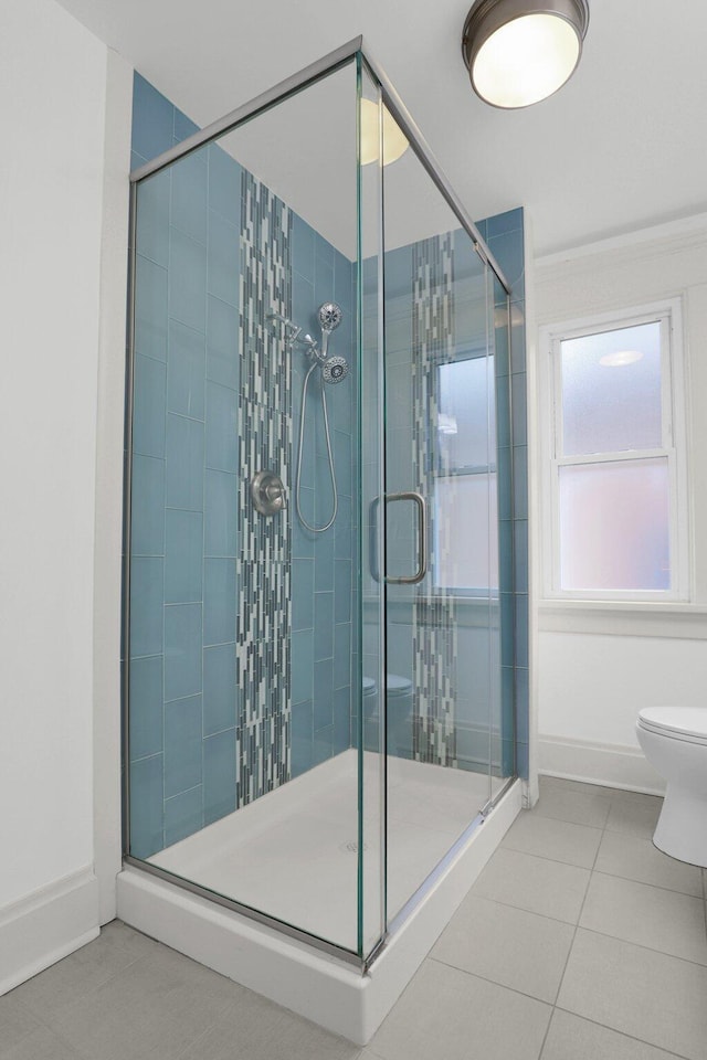 bathroom featuring tile patterned floors, toilet, and a shower with door