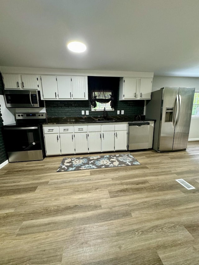 kitchen featuring white cabinets, sink, decorative backsplash, appliances with stainless steel finishes, and light hardwood / wood-style floors