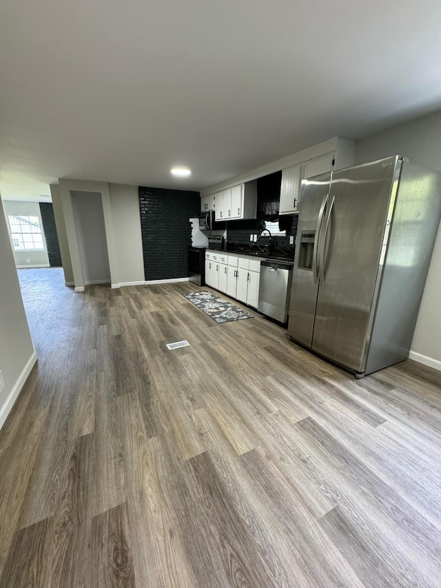 kitchen with sink, white cabinets, light wood-type flooring, and appliances with stainless steel finishes