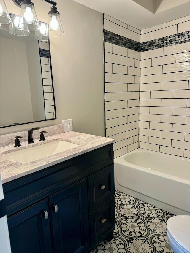 full bathroom featuring vanity, tiled shower / bath, and toilet