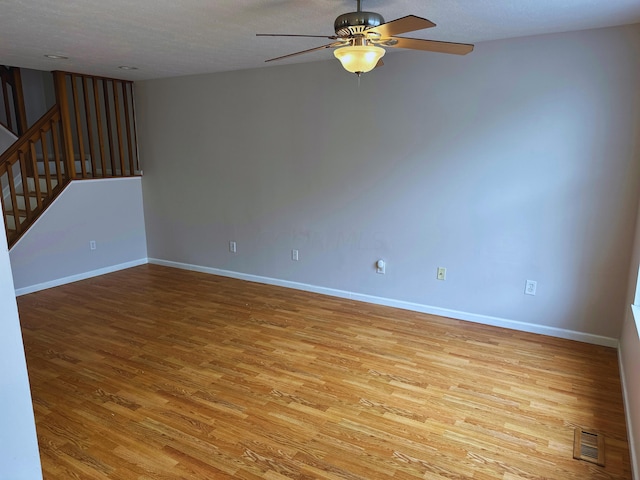 unfurnished room with a textured ceiling, light wood-type flooring, and ceiling fan