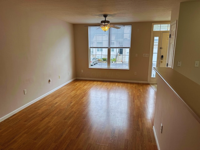 unfurnished room with ceiling fan, light wood-type flooring, and a textured ceiling