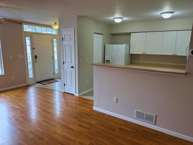 foyer entrance featuring a textured ceiling and light wood-type flooring