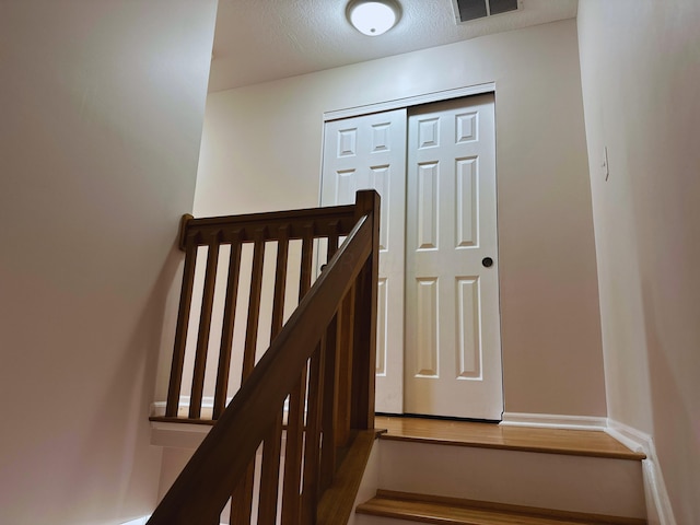 stairway featuring a textured ceiling