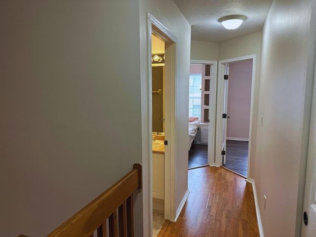 hall with light wood-type flooring and a textured ceiling