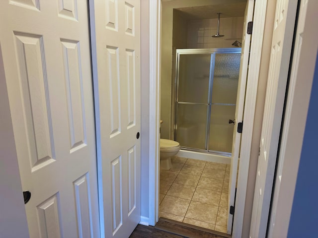 bathroom featuring toilet, wood-type flooring, and a shower with door