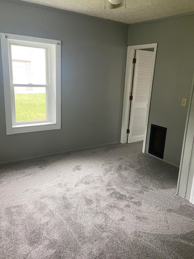 carpeted empty room featuring a textured ceiling