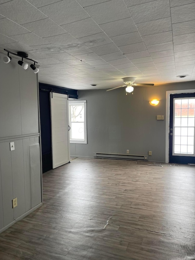 unfurnished room with hardwood / wood-style flooring, ceiling fan, rail lighting, and a baseboard radiator