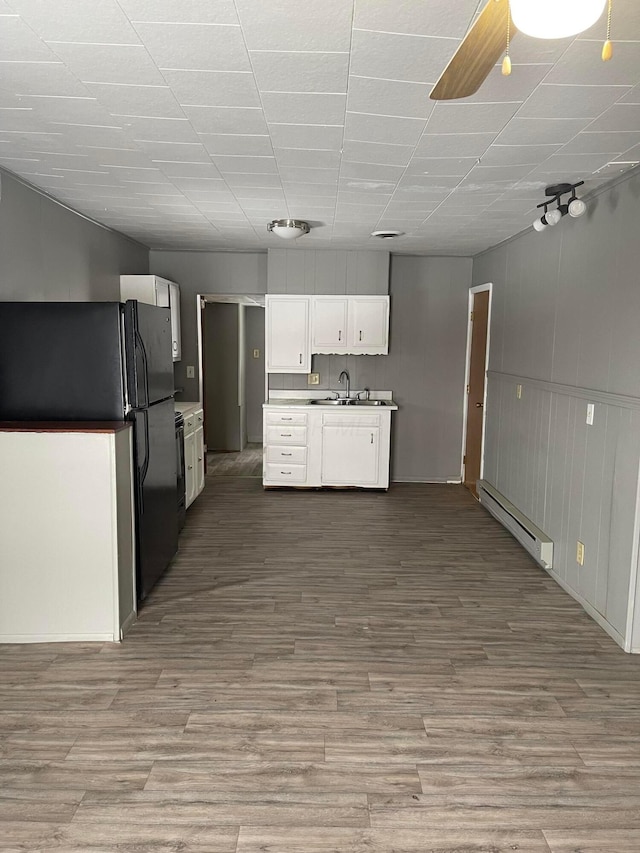 kitchen featuring white cabinets, black fridge, sink, hardwood / wood-style flooring, and a baseboard radiator