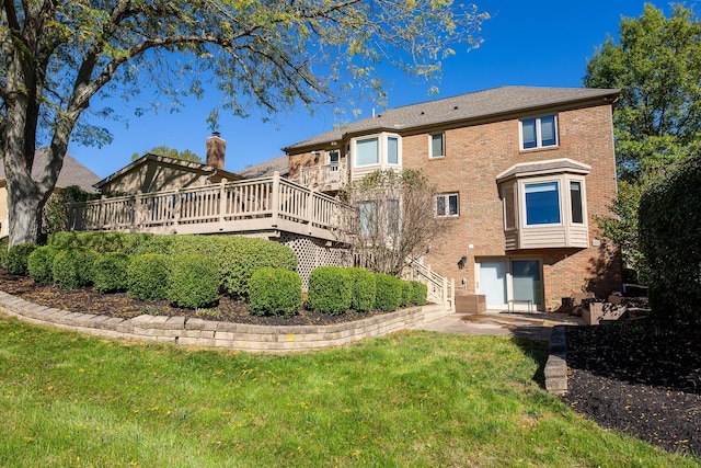 back of house featuring a lawn, a patio area, and a wooden deck