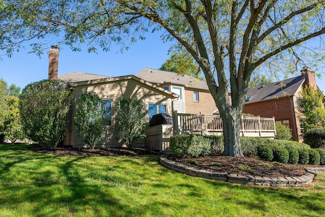 rear view of house featuring a lawn and a wooden deck