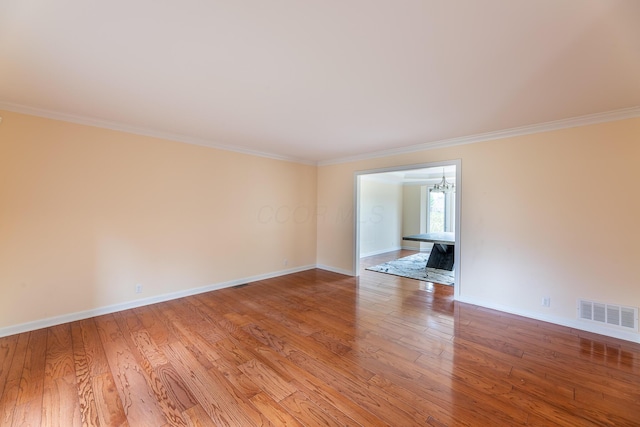 unfurnished living room featuring light wood-type flooring, crown molding, and an inviting chandelier