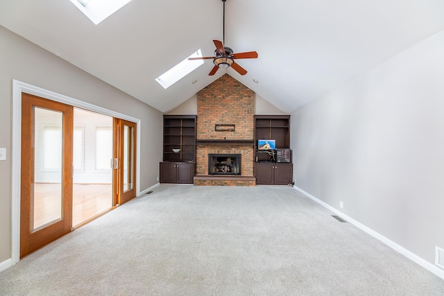 unfurnished living room featuring carpet, a brick fireplace, lofted ceiling with skylight, ceiling fan, and built in features