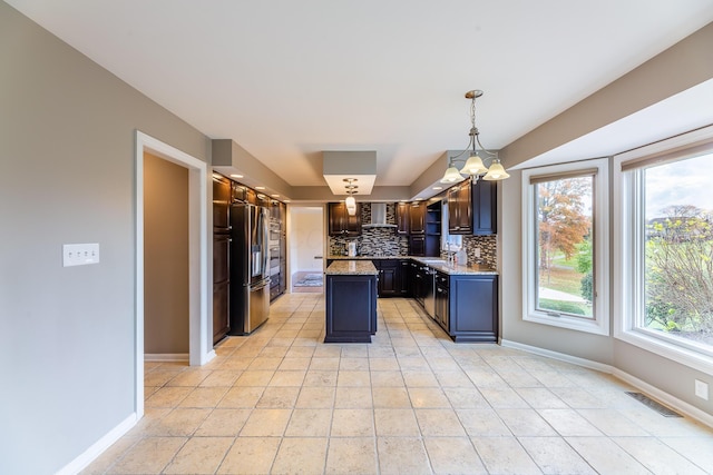 kitchen featuring a center island, wall chimney exhaust hood, stainless steel refrigerator with ice dispenser, pendant lighting, and decorative backsplash