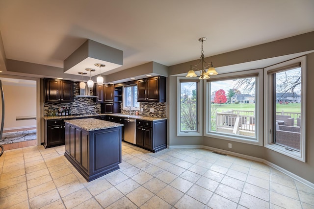 kitchen featuring tasteful backsplash, a kitchen island, hanging light fixtures, and stainless steel dishwasher