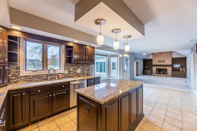 kitchen with backsplash, stainless steel dishwasher, a fireplace, a kitchen island, and light stone counters