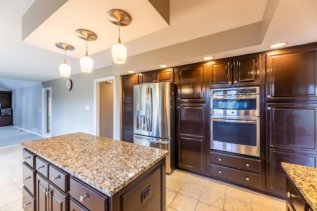 kitchen featuring a raised ceiling, light stone counters, pendant lighting, and stainless steel appliances