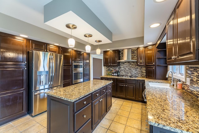 kitchen featuring stainless steel appliances, a kitchen island, hanging light fixtures, and wall chimney range hood