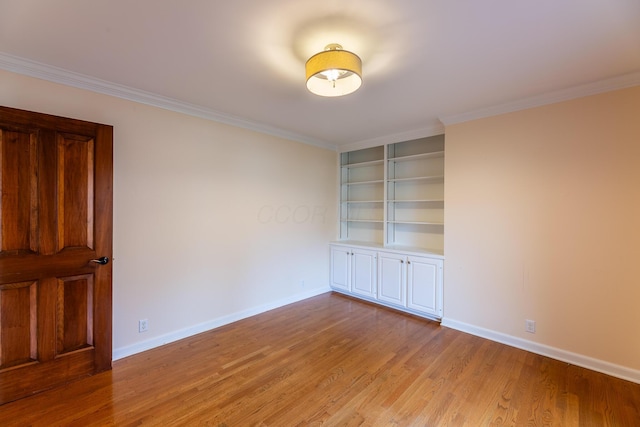 spare room with light wood-type flooring and crown molding