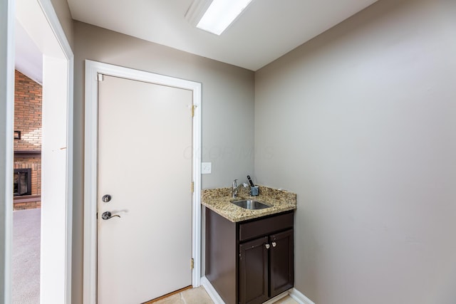 bathroom with vanity, lofted ceiling, and a brick fireplace