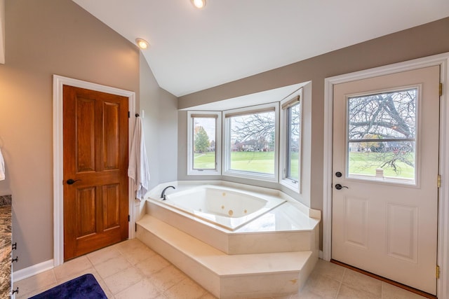 bathroom featuring tile patterned flooring, a relaxing tiled tub, a healthy amount of sunlight, and lofted ceiling