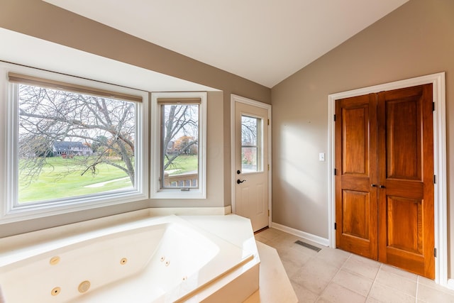 bathroom with a bathing tub, tile patterned flooring, and lofted ceiling