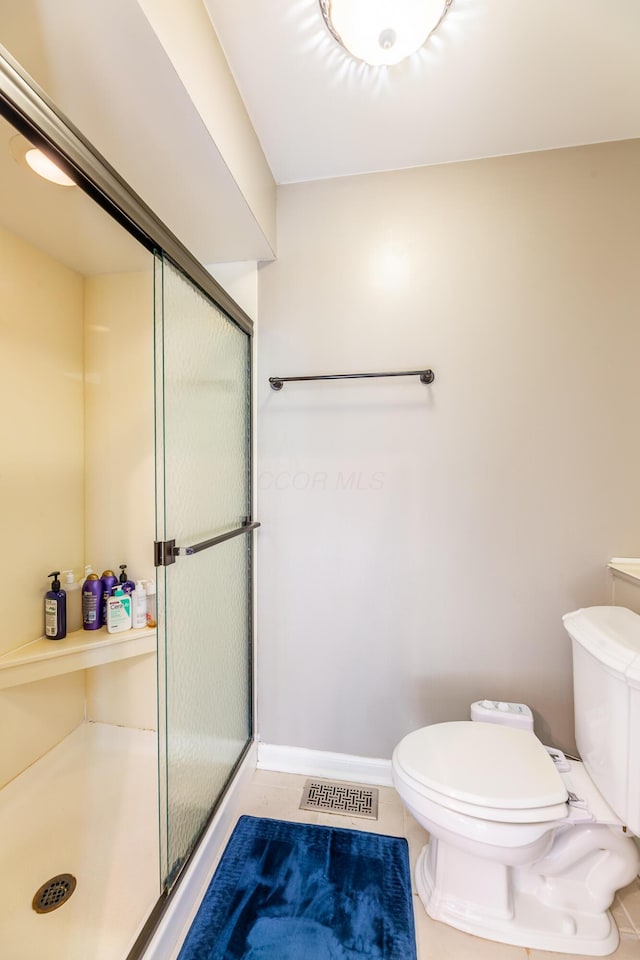 bathroom with toilet, tile patterned floors, and walk in shower