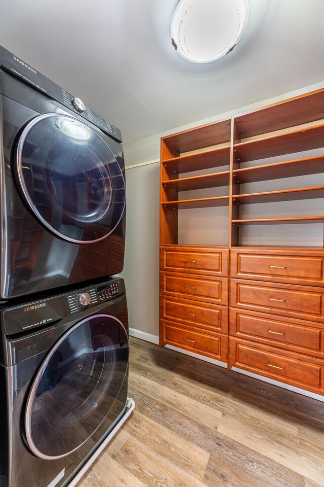 laundry area featuring wood-type flooring and stacked washer and dryer