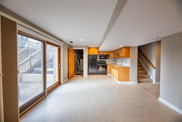 kitchen featuring light stone countertops, sink, light tile patterned flooring, and black appliances