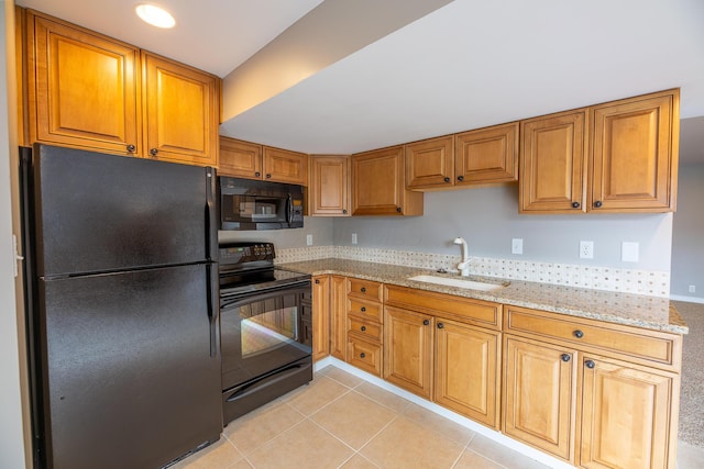 kitchen featuring light stone counters, sink, light tile patterned floors, and black appliances