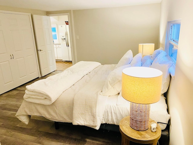 bedroom featuring wood-type flooring and white fridge with ice dispenser