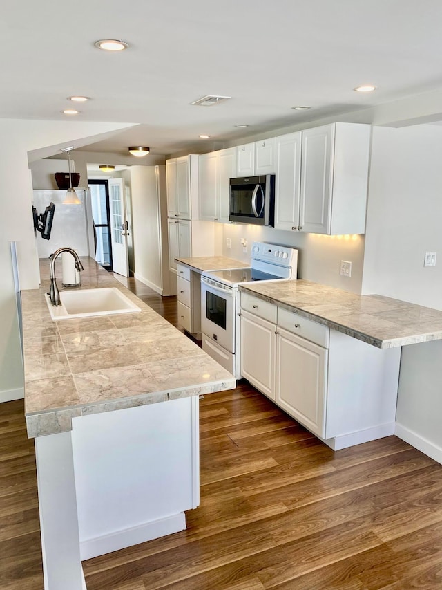 kitchen featuring stainless steel appliances, white cabinetry, wood-type flooring, and sink